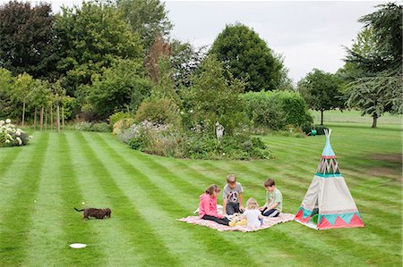 dog sitting down back view - Children having picnic beside teepee Stock Photo - Premium Royalty-Free, Code: 649-03447775