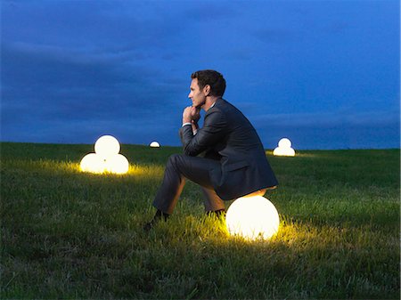 energy concept - Man sitting on a lightball Stock Photo - Premium Royalty-Free, Code: 649-03466029