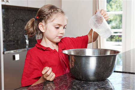 Girl pouring water in to mixing bowl Stock Photo - Premium Royalty-Free, Code: 649-03768888