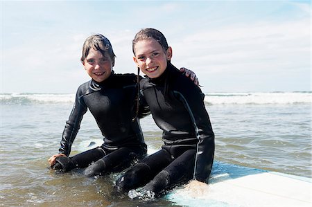 Children sitting on surf board in the se Stock Photo - Premium Royalty-Free, Code: 649-03768923