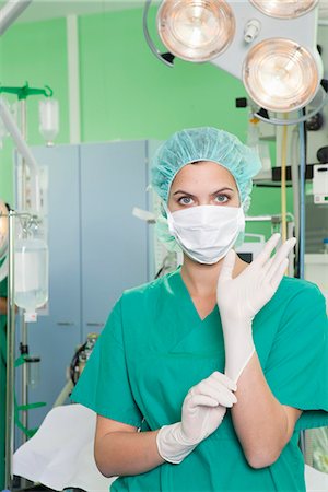 doctor posing - Nurse in scrubs putting on gloves Stock Photo - Premium Royalty-Free, Code: 649-03774475