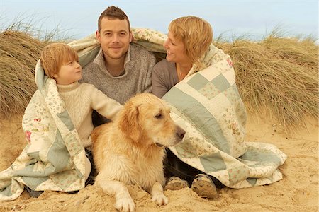 Family with dog, under quilt, on beach Stock Photo - Premium Royalty-Free, Code: 649-03773180