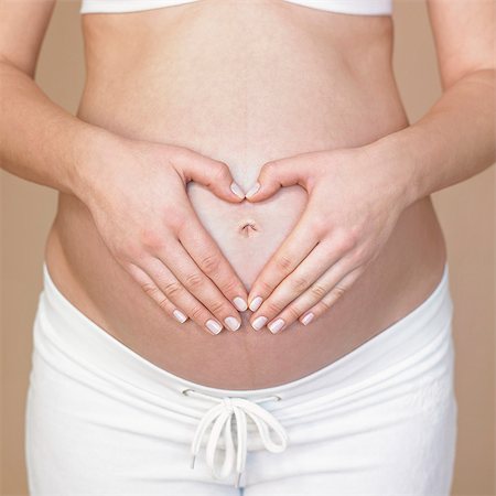 Hands forming heart on pregnancy bump Stock Photo - Premium Royalty-Free, Code: 649-03796568