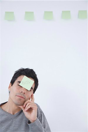 Man with 'busy' post-it note on his head Stock Photo - Premium Royalty-Free, Code: 649-03817631