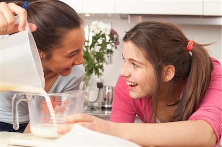 friends cooking inside - teenage girls measuring milk in kitchen Stock Photo - Premium Royalty-Free, Code: 649-03818444