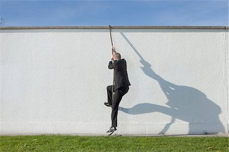 possibilities - Businessman climbing over wall with rope Stock Photo - Premium Royalty-Free, Code: 649-03857389