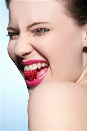 raspberry - Smiling woman eating a raspberry Stock Photo - Premium Royalty-Free, Code: 649-03857973