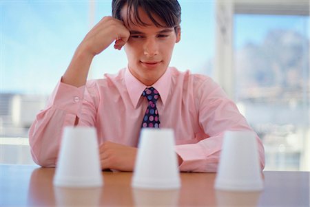 Businessman examining cups in office Stock Photo - Premium Royalty-Free, Code: 649-03858693