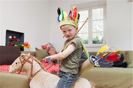 funny images of indian people - Boy in war bonnet playing with toys Stock Photo - Premium Royalty-Free, Code: 649-03884188
