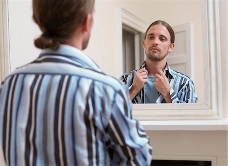 dressing - Man adjusting his shirt in mirror Stock Photo - Premium Royalty-Free, Code: 649-03881944