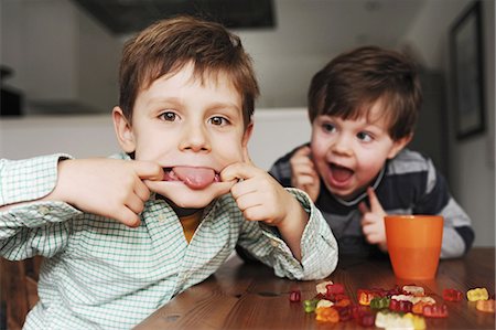 Boys making faces at table Stock Photo - Premium Royalty-Free, Code: 649-03883224