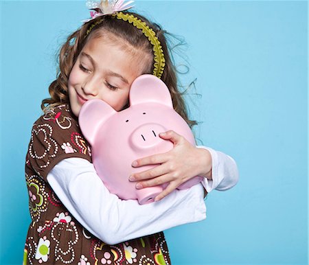 Girl (8-9) embracing piggybank, studio shot Stock Photo - Premium Royalty-Free, Code: 640-05760832