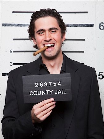 prison photograph - Studio mugshot of young man smoking cigar Stock Photo - Premium Royalty-Free, Code: 640-05760905