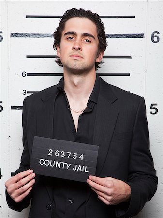 people with a jail sign - Studio mugshot of young man Stock Photo - Premium Royalty-Free, Code: 640-05760906