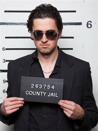 people with a jail sign - Studio mugshot of young man wearing sunglasses Stock Photo - Premium Royalty-Free, Code: 640-05760907