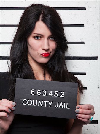 people with a jail sign - Studio mugshot of young woman Stock Photo - Premium Royalty-Free, Code: 640-05760902