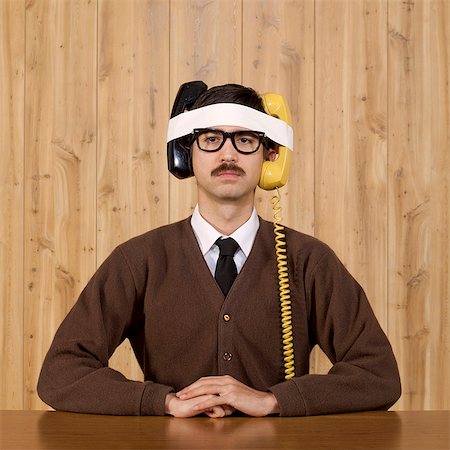 Businessman with telephones strapped to head in office Stock Photo - Premium Royalty-Free, Code: 640-05761206