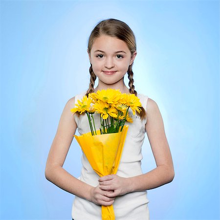 Studio portrait of girl (10-11) holding bunch of yellow flowers Stock Photo - Premium Royalty-Free, Code: 640-05761256