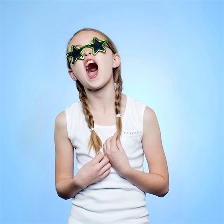 Studio portrait of girl (10-11) wearing star shaped glasses singing Stock Photo - Premium Royalty-Free, Code: 640-05761257