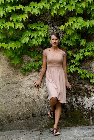 Italy, Ravello, Portrait of woman in dress leaning overgrown wall Stock Photo - Premium Royalty-Free, Code: 640-06050023