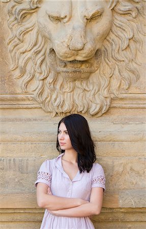 Italy, Florence, Portrait of young attractive woman with lion sculpture in background Stock Photo - Premium Royalty-Free, Code: 640-06050202