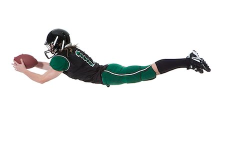 diving (not water) - Male player of American football catching ball, studio shot Stock Photo - Premium Royalty-Free, Code: 640-06963149