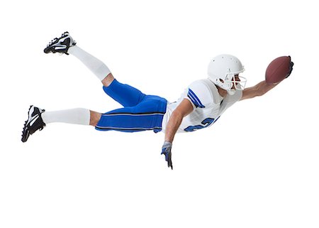 diving (not water) - Male player of American football catching ball, studio shot Stock Photo - Premium Royalty-Free, Code: 640-06963150