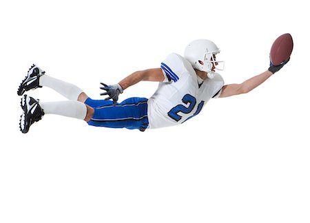 diving (not water) - Male player of American football catching ball, studio shot Stock Photo - Premium Royalty-Free, Code: 640-06963151