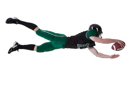 diving (not water) - Male player of American football catching ball, studio shot Stock Photo - Premium Royalty-Free, Code: 640-06963166