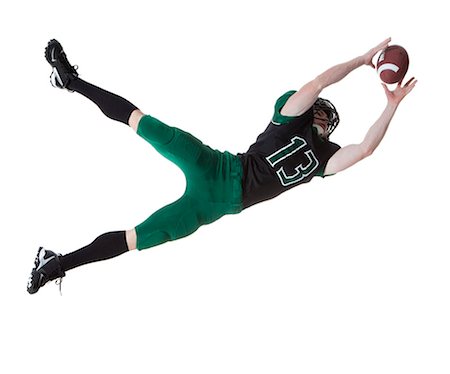 diving (not water) - Male player of American football catching ball, studio shot Stock Photo - Premium Royalty-Free, Code: 640-06963167