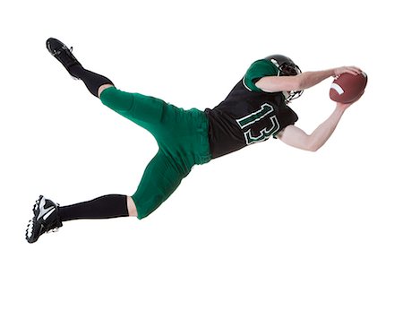diving (not water) - Male player of American football catching ball, studio shot Stock Photo - Premium Royalty-Free, Code: 640-06963168