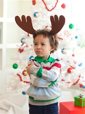 Happy young boy deer horns standing  in front of Christmas tree Stock Photo - Premium Royalty-Free, Code: 640-06963457