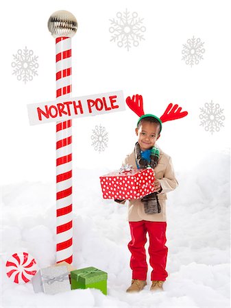 Boy (4-5) wearing reindeer antlers standing next to North Pole sign Stock Photo - Premium Royalty-Free, Code: 640-06963743