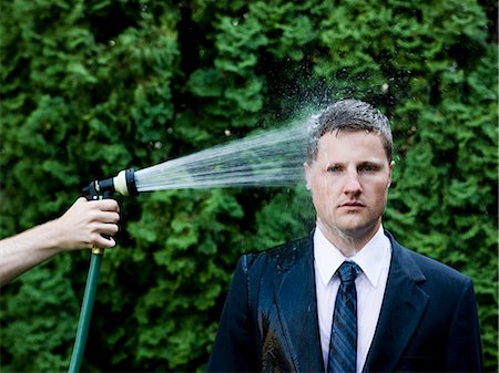 drenched - man in a suit and tie getting sprayed in the head with a hose Stock Photo - Premium Royalty-Free, Code: 640-08089140