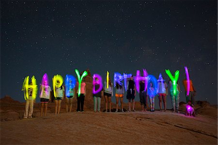 Time lapse view of friends writing Happy Birthday on remote desert hilltop under starry night sky Stock Photo - Premium Royalty-Free, Code: 640-08546208