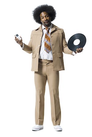 Man with an afro in beige suit listening to MP3 player Stock Photo - Premium Royalty-Free, Code: 640-01349490