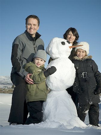 Portrait of a family standing next to a snowman Stock Photo - Premium Royalty-Free, Code: 640-01349578