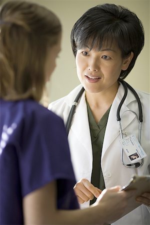physician consulting backview - A female doctor and female nurse talking Stock Photo - Premium Royalty-Free, Code: 640-01349595