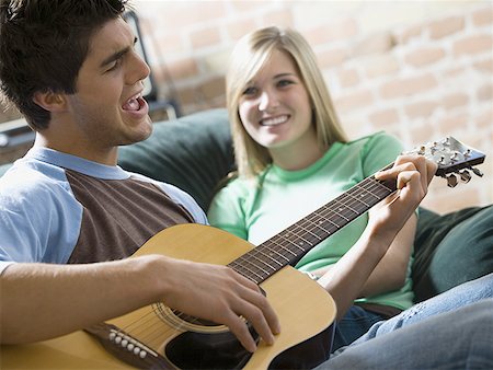 picture of the blue playing a instruments - Close-up of a young woman watching a young man a play guitar Stock Photo - Premium Royalty-Free, Code: 640-01349692