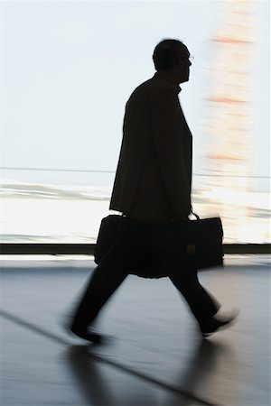 Silhouette of a businessman walking with a briefcase Stock Photo - Premium Royalty-Free, Code: 640-01349942