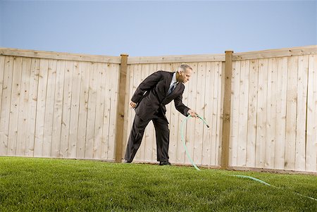 Low angle view of a businessman watering with a hose Stock Photo - Premium Royalty-Free, Code: 640-01354214