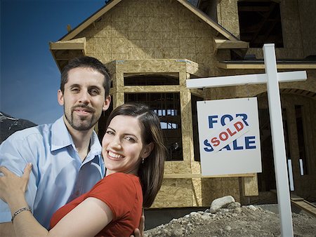 retail development - Portrait of a young couple smiling in front of a house Stock Photo - Premium Royalty-Free, Code: 640-01354231