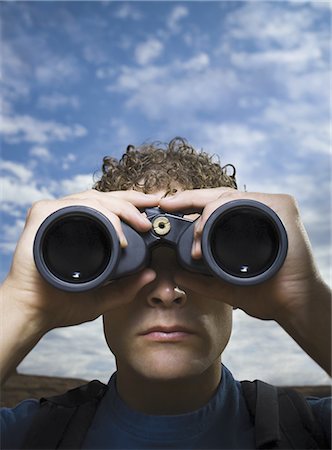 enigma - Close-up of a young man looking through binoculars Stock Photo - Premium Royalty-Free, Code: 640-01354446