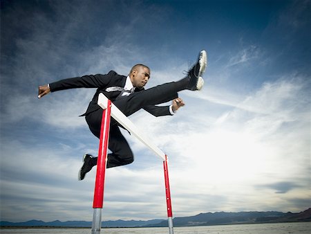 flier - Low angle view of a businessman jumping over a hurdle in a race Stock Photo - Premium Royalty-Free, Code: 640-01354713