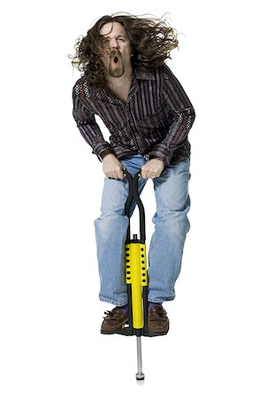 Portrait of a young man standing on a pogo stick Stock Photo - Premium Royalty-Free, Code: 640-01354906