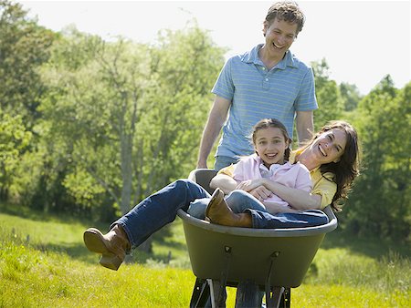 propulsion - man pushing his daughter and his wife in a wheelbarrow Stock Photo - Premium Royalty-Free, Code: 640-01354987