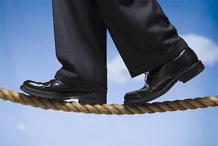 Closeup of male feet in dress shoes walking on rope outdoors Stock Photo - Premium Royalty-Free, Code: 640-01355084