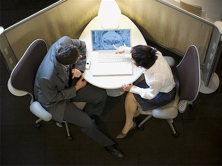 High angle view of a businesswoman and a businessman looking at a laptop Stock Photo - Premium Royalty-Free, Code: 640-01355277