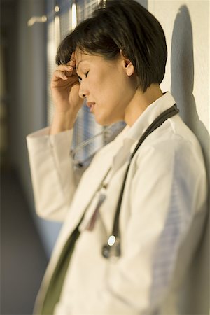 simsearch:640-01364042,k - Profile of a female doctor with her hand on her forehead Stock Photo - Premium Royalty-Free, Code: 640-01355646