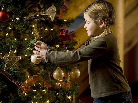 Girl with Christmas bauble and Christmas tree Stock Photo - Premium Royalty-Free, Code: 640-01355694